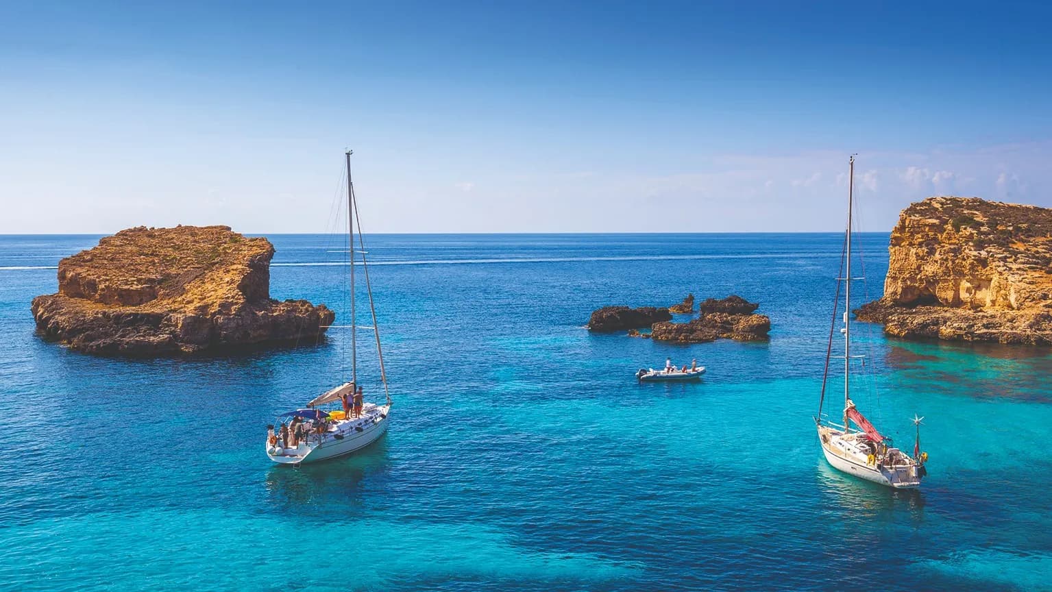 Veleros fondeados en el agua turquesa de la Blue Lagoon de Comino, entre los islotes de roca