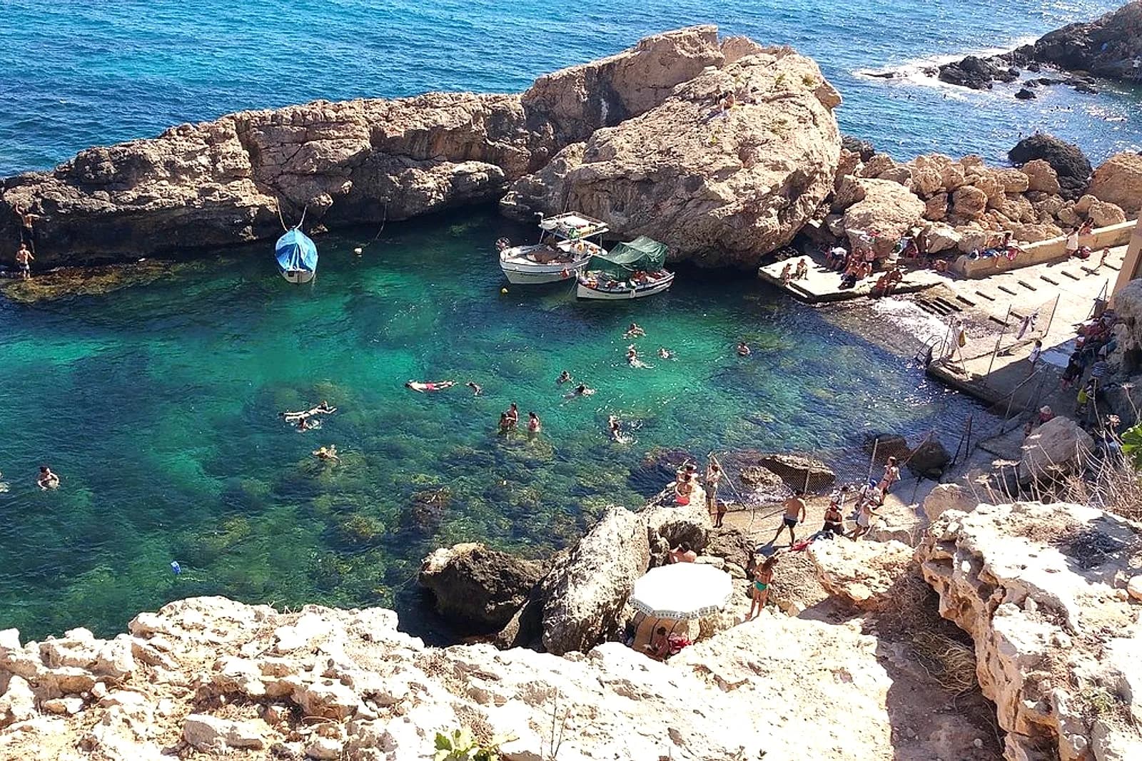 Għar Lapsi, con gente bañándose entre las rocas en el agua transparente