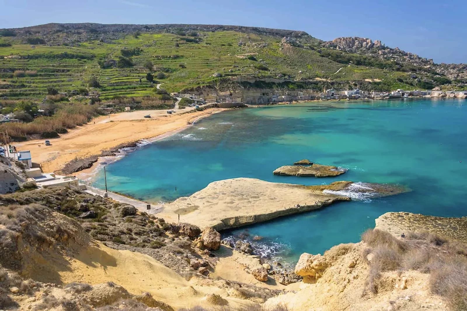 Ġnejna Bay desde lo alto, con la playa de arena, la losa de roca plana y el valle de terrazas detrás