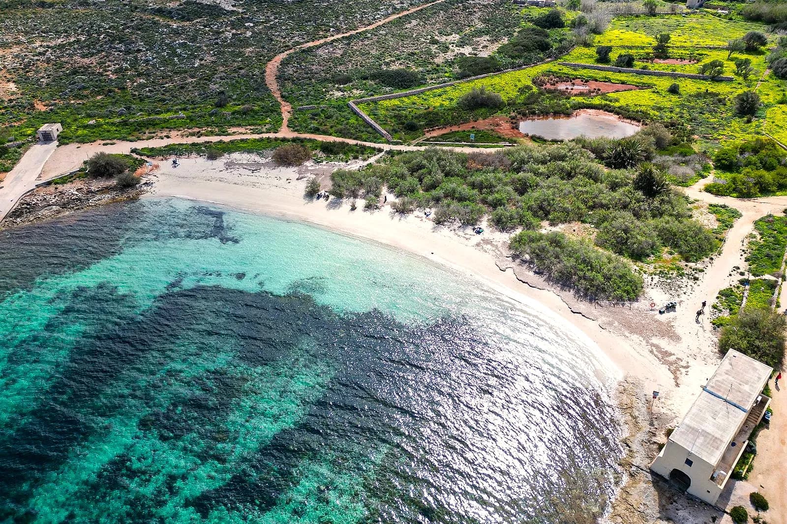 Santa Marija Bay desde el aire: la media luna de arena, el agua turquesa y los tamariscos junto a la orilla